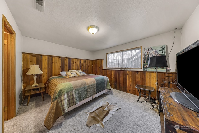 bedroom with a textured ceiling, carpet floors, and wooden walls