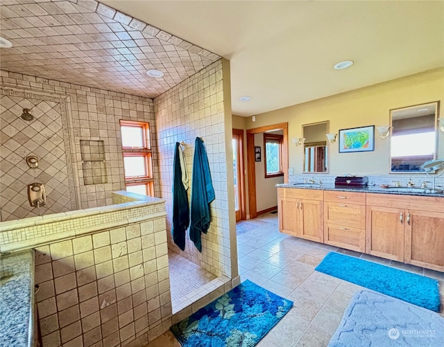 bathroom with tiled shower, vanity, a wealth of natural light, and tile patterned flooring