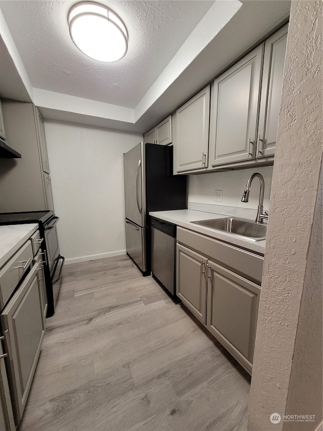 kitchen featuring electric range oven, stainless steel dishwasher, a textured ceiling, sink, and light hardwood / wood-style flooring