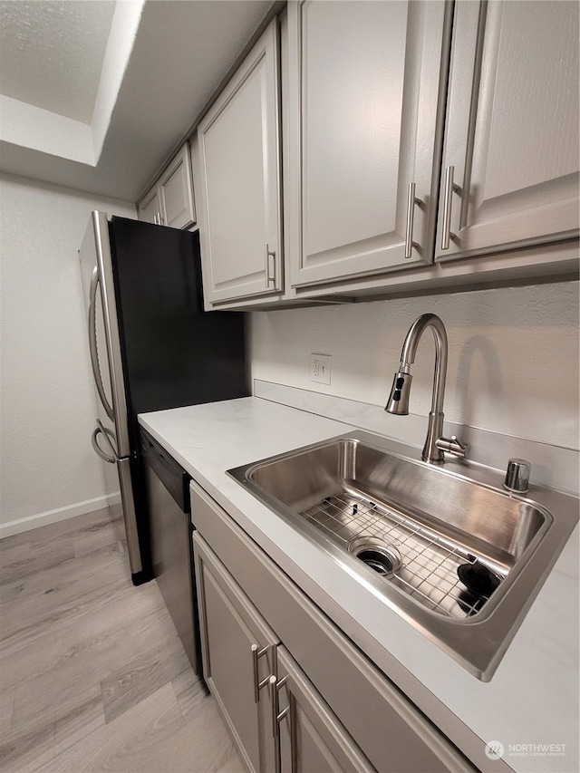 kitchen featuring light hardwood / wood-style floors, stainless steel dishwasher, and sink