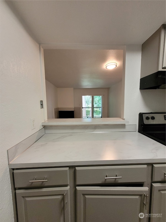 kitchen with gray cabinets, light stone counters, and stove