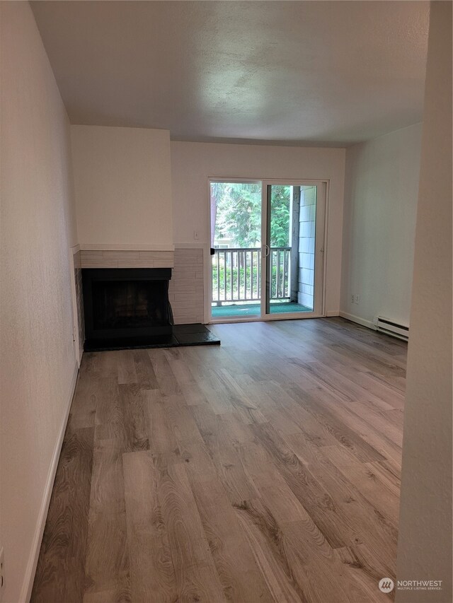 unfurnished living room featuring a baseboard radiator and light hardwood / wood-style floors