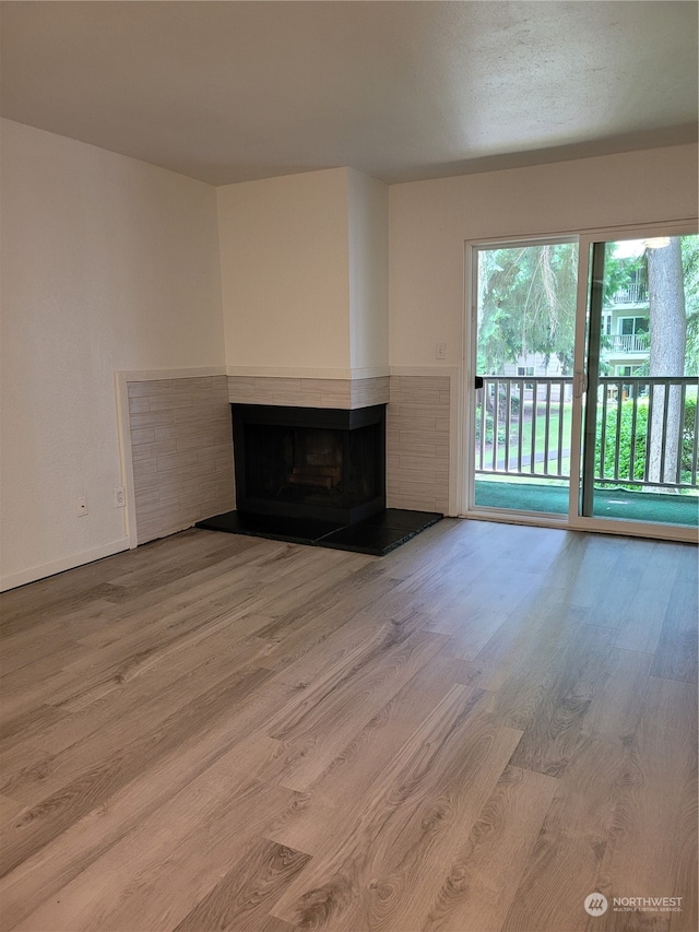 unfurnished living room featuring a multi sided fireplace and hardwood / wood-style floors