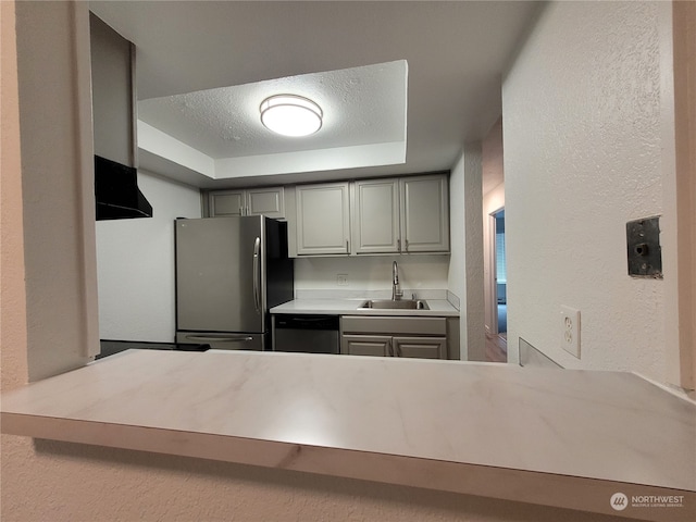 kitchen featuring appliances with stainless steel finishes, a raised ceiling, gray cabinetry, and sink