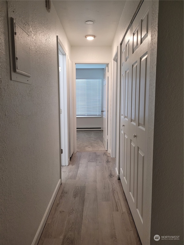 hallway featuring a baseboard heating unit and light wood-type flooring