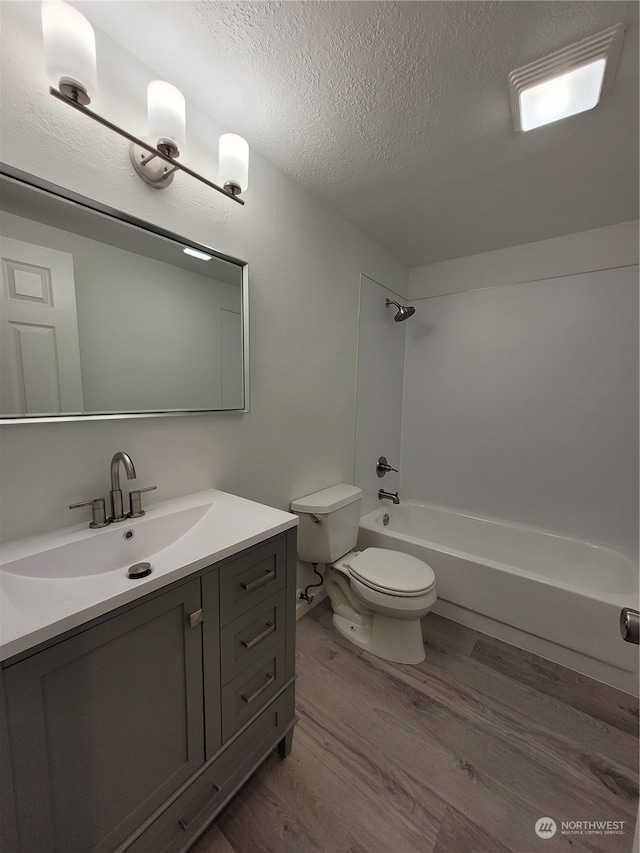 full bathroom featuring vanity, a textured ceiling, wood-type flooring, shower / tub combination, and toilet