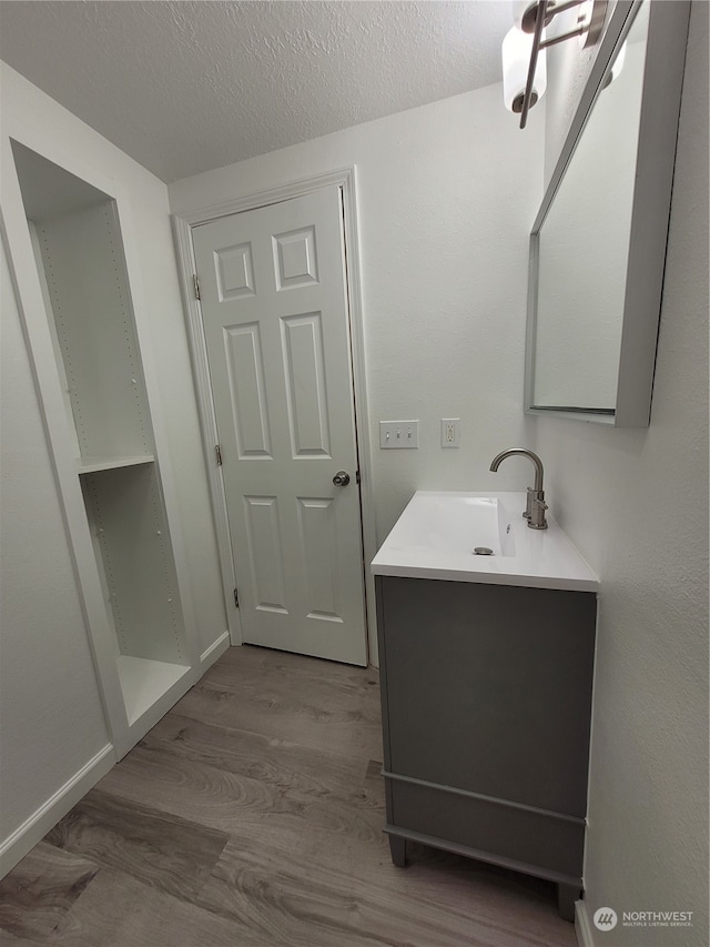 bathroom featuring vanity, wood-type flooring, and a textured ceiling