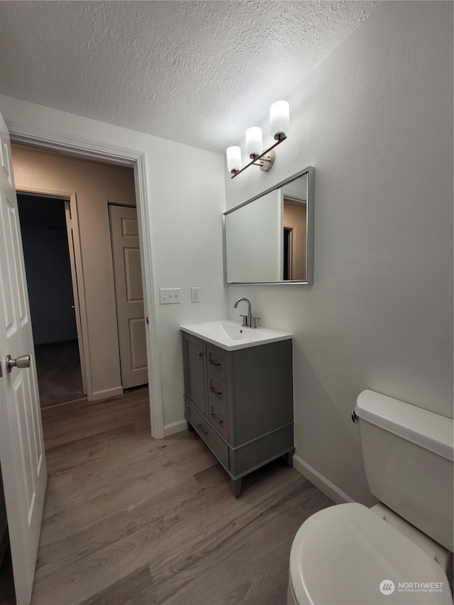 bathroom with vanity, a textured ceiling, hardwood / wood-style flooring, and toilet