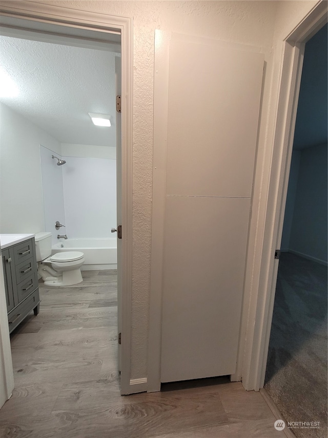 full bathroom featuring toilet, vanity, a textured ceiling, and tub / shower combination