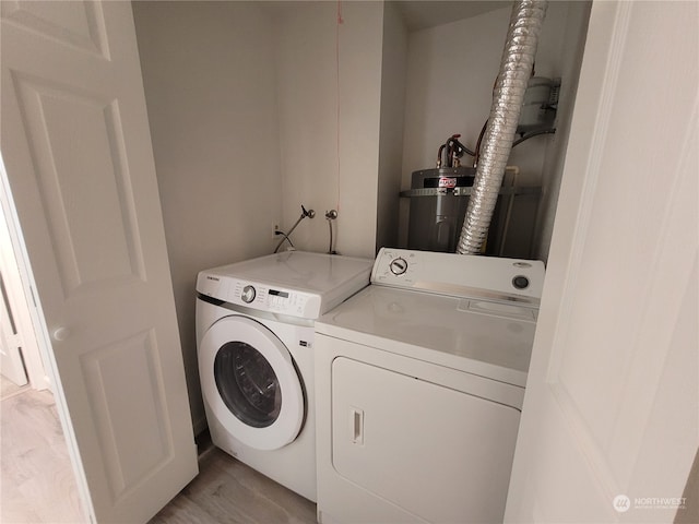 clothes washing area with separate washer and dryer, water heater, and light wood-type flooring