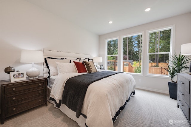 bedroom with light colored carpet and multiple windows