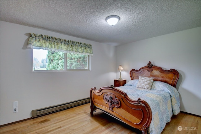 bedroom featuring a baseboard heating unit, a textured ceiling, and hardwood / wood-style flooring