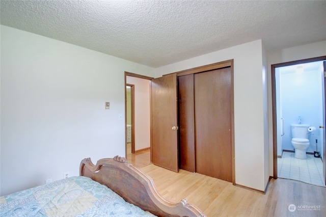 bedroom with ensuite bathroom, a textured ceiling, a closet, and light wood-type flooring