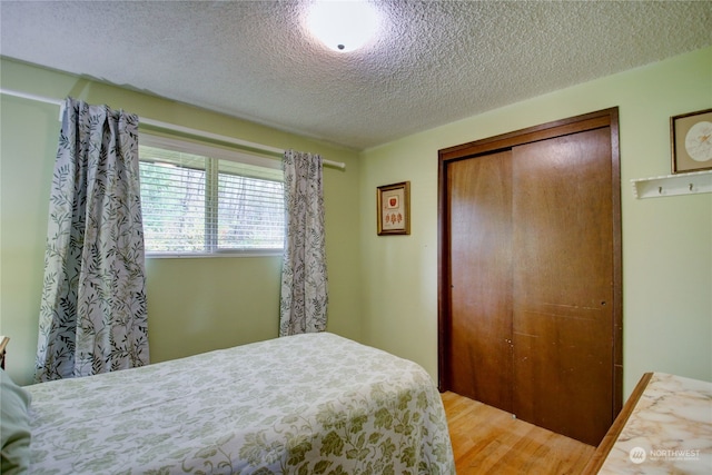 bedroom with wood-type flooring, a textured ceiling, and a closet