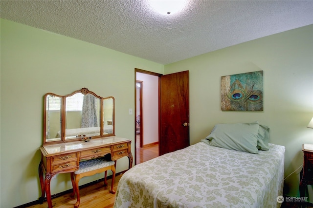 bedroom with light hardwood / wood-style floors and a textured ceiling