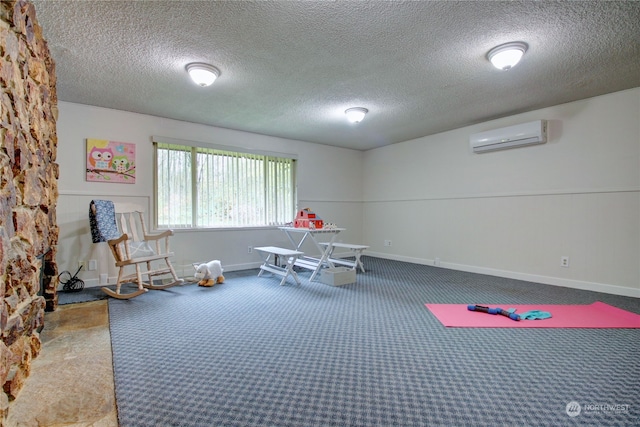 rec room with a wall unit AC, a textured ceiling, and carpet floors