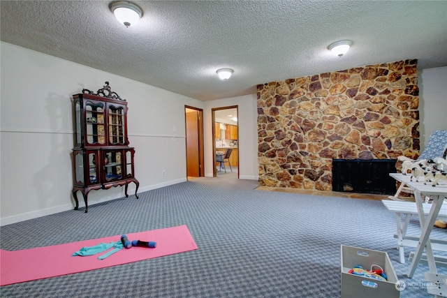 interior space featuring a stone fireplace, carpet, and a textured ceiling