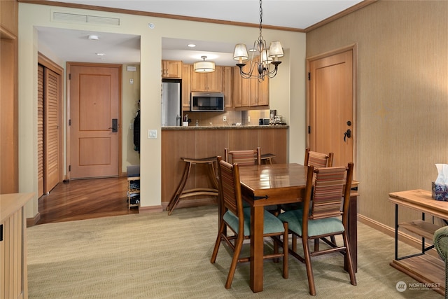 dining space with an inviting chandelier, ornamental molding, and light hardwood / wood-style flooring