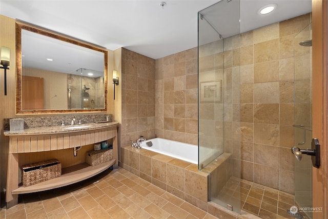 bathroom featuring tile walls, shower with separate bathtub, and sink