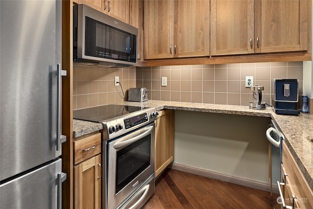 kitchen with backsplash, dark hardwood / wood-style flooring, light stone counters, and appliances with stainless steel finishes