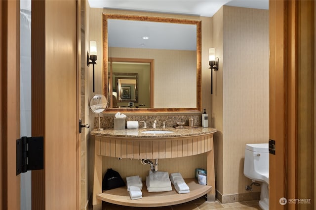 bathroom with tile patterned flooring, sink, decorative backsplash, and toilet