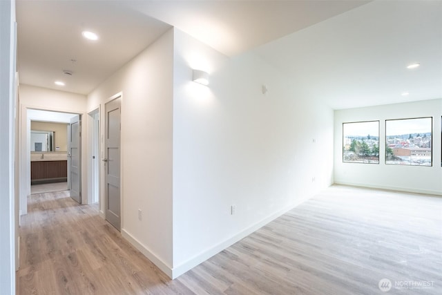 hallway featuring light wood-type flooring, baseboards, and recessed lighting