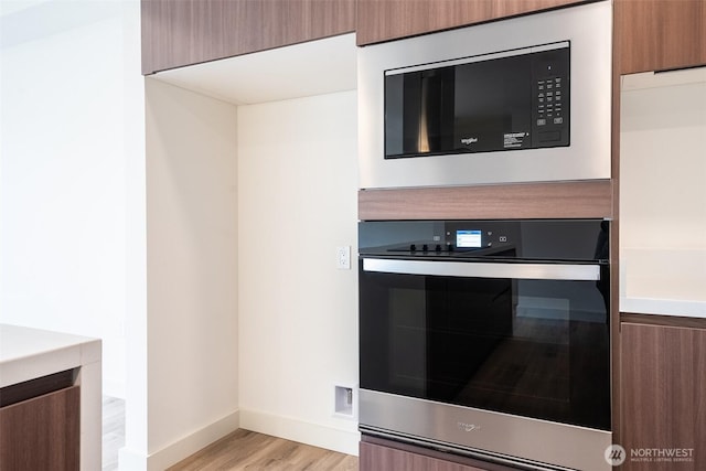 details with brown cabinets, built in microwave, light countertops, and modern cabinets