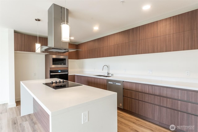 kitchen with light countertops, a sink, island range hood, modern cabinets, and black appliances