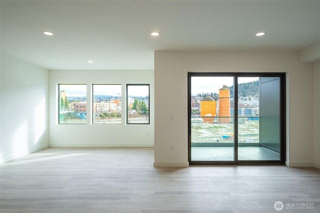 spare room with light wood-type flooring, recessed lighting, and plenty of natural light