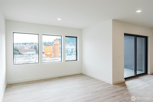 unfurnished room with baseboards, recessed lighting, and light wood-style floors