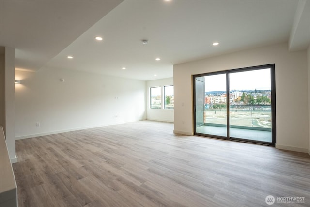 spare room with baseboards, light wood-style flooring, and recessed lighting