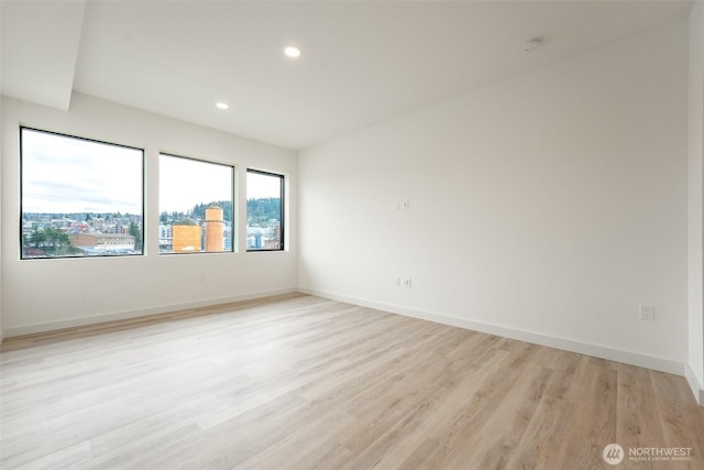 spare room featuring light wood-style floors, baseboards, and recessed lighting