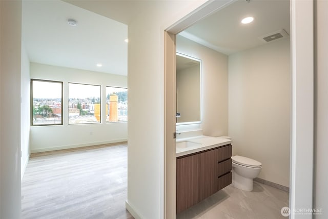 bathroom featuring visible vents, baseboards, toilet, vanity, and recessed lighting