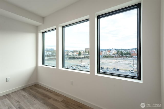 spare room with a city view, baseboards, and wood finished floors