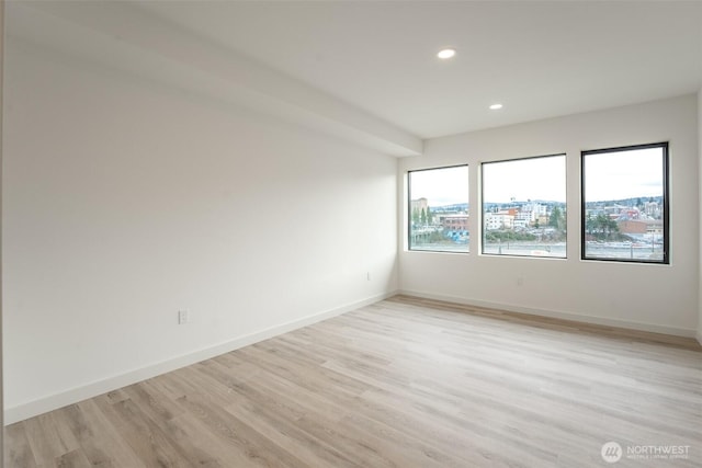 spare room featuring recessed lighting, light wood-style flooring, and baseboards