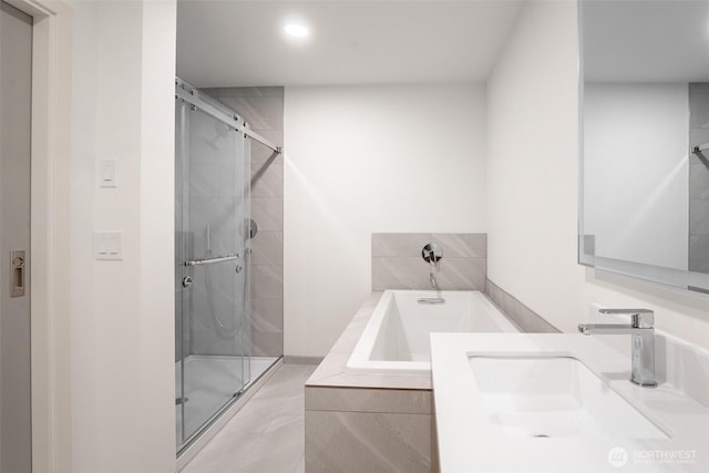 bathroom featuring a stall shower, a bath, and vanity