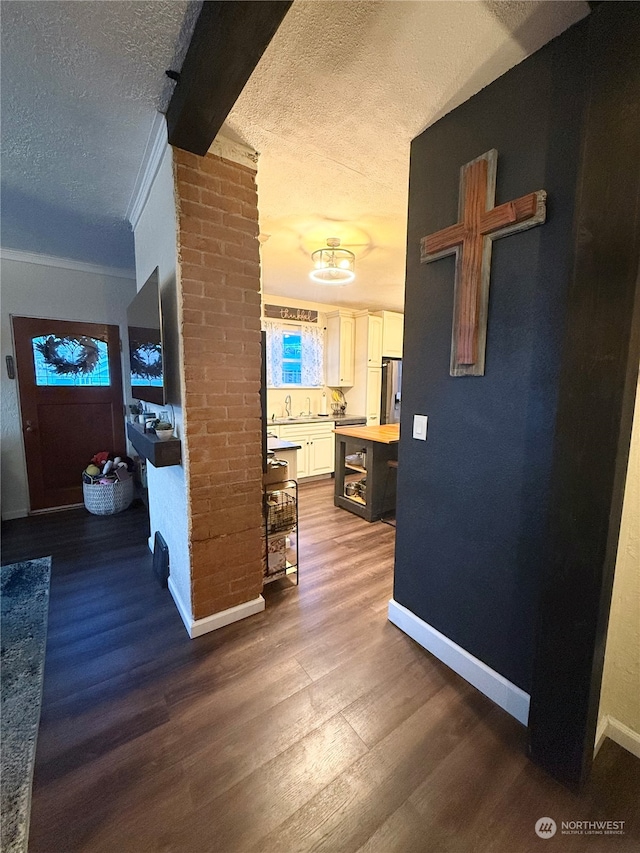 hall with wood-type flooring, a textured ceiling, and crown molding