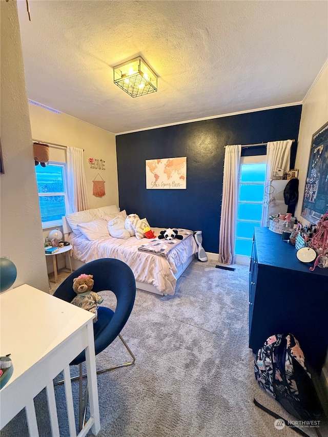 bedroom with a textured ceiling, ornamental molding, and carpet floors