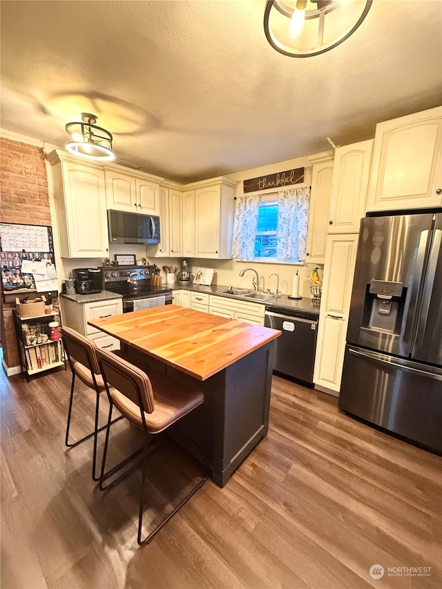 kitchen featuring wood-type flooring, stainless steel appliances, a textured ceiling, wood counters, and sink