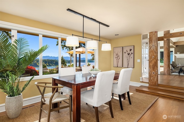 dining area featuring wood-type flooring, a water and mountain view, and plenty of natural light