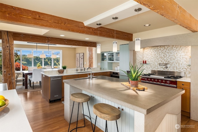 kitchen with a breakfast bar area, a large island with sink, pendant lighting, and beam ceiling