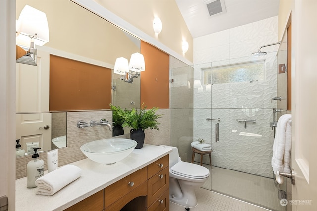 bathroom with tile patterned flooring, toilet, tiled shower, vanity, and tile walls