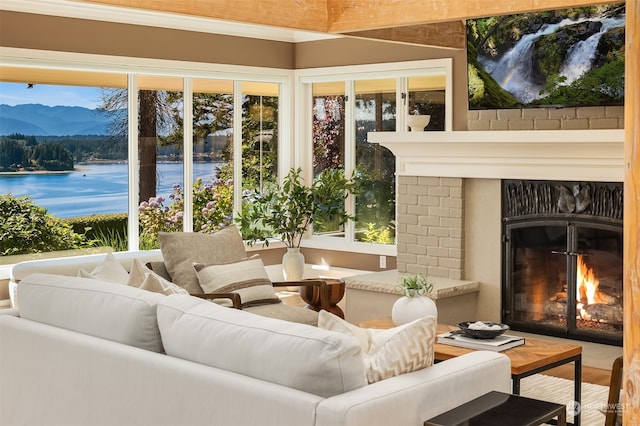 sunroom featuring a fireplace, a water view, and plenty of natural light