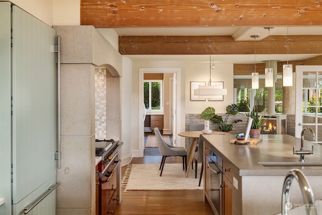 kitchen with beamed ceiling, high end stainless steel range oven, refrigerator, decorative light fixtures, and dark hardwood / wood-style floors