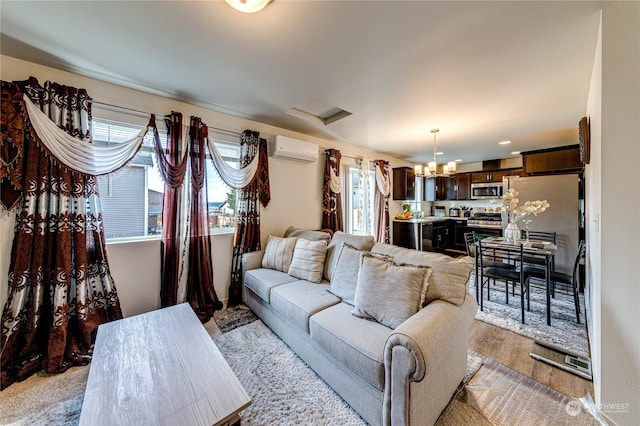 living room with a wall mounted AC, light wood-style flooring, and an inviting chandelier