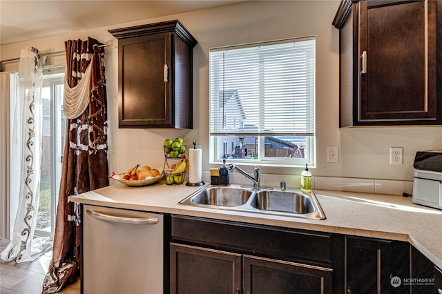 kitchen featuring light countertops, stainless steel dishwasher, a sink, and dark brown cabinetry