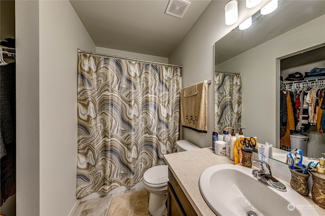 bathroom featuring toilet, vanity, visible vents, a shower with curtain, and a walk in closet