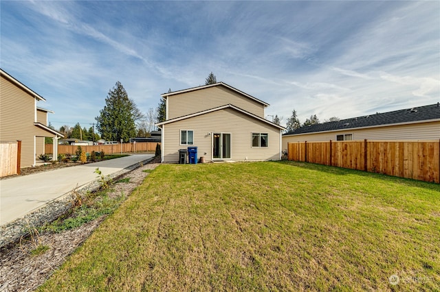 back of house featuring a yard, concrete driveway, and fence