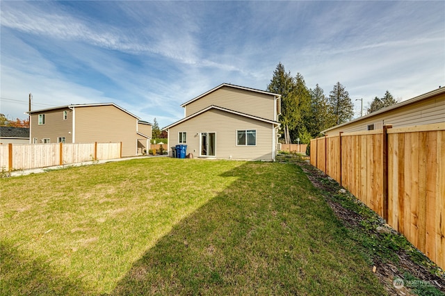 back of house with a fenced backyard and a lawn