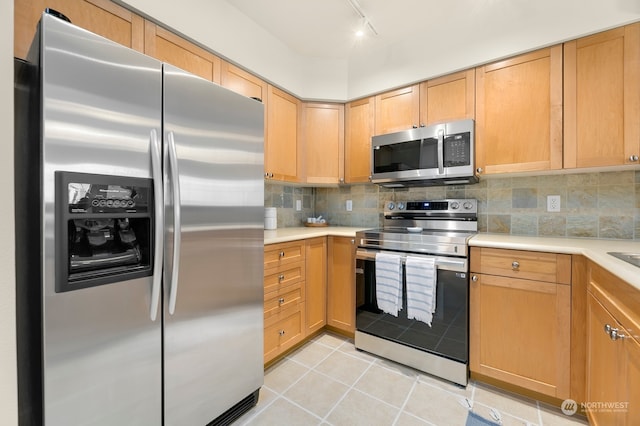 kitchen featuring backsplash, light tile patterned flooring, track lighting, and appliances with stainless steel finishes